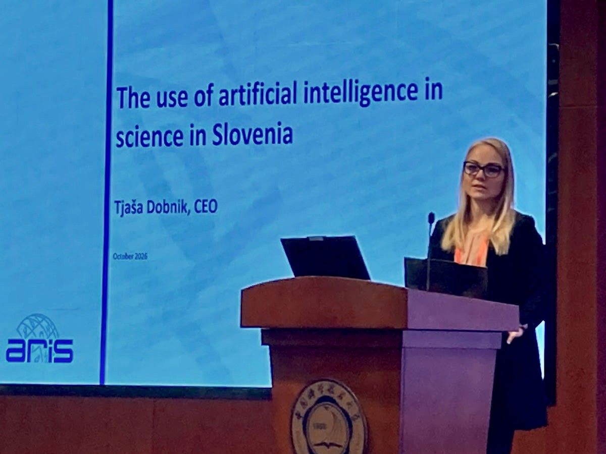 Direktorica ARIS predstavlja temo uporabe umetne inteligence v znanosti v Sloveniji na mednarodnem dogodku. Govori za govorniškim pultom, za njo pa je projekcijski zaslon s predstavitvijo.